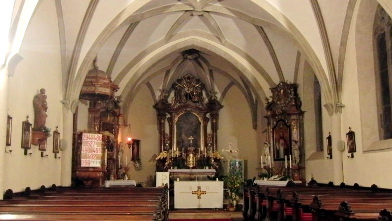 Innenansicht einer Kirche mit Altar und Bänken.