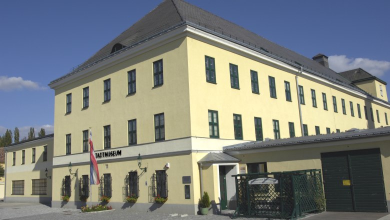 Gelbes Gebäude mit der Aufschrift "Stadtmuseum" und einer österreichischen Flagge davor.