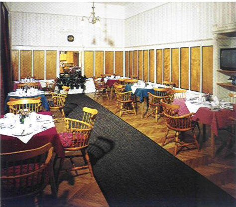 A breakfast room with laid tables and wooden furniture.