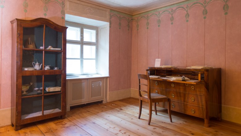 Historischer Raum mit antikem Schrank und Schreibtisch.