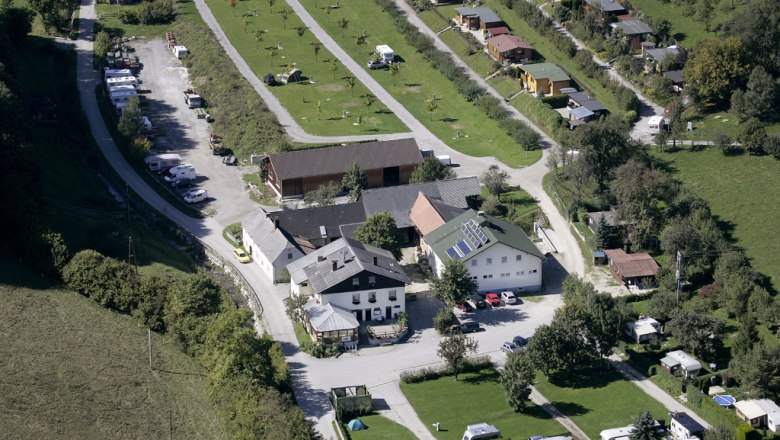 Aerial view of a campsite with caravans and buildings in a green landscape.