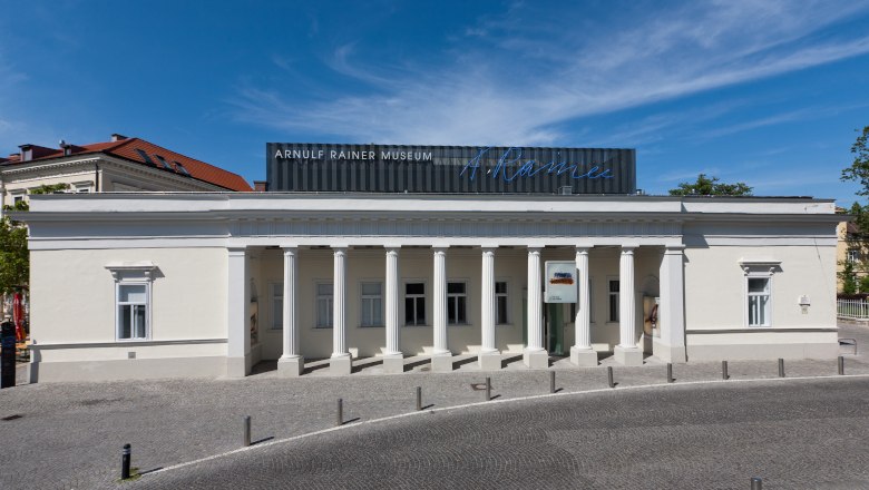 Außenansicht des Arnulf Rainer Museums mit Säulenfassade und blauem Himmel.