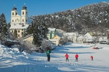 Winterlandschaft mit Kirche und Skilangl&auml;ufern.