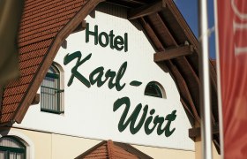 Fassade des Hotels Karl-Wirt mit rotem Dach und grünen Fensterläden.