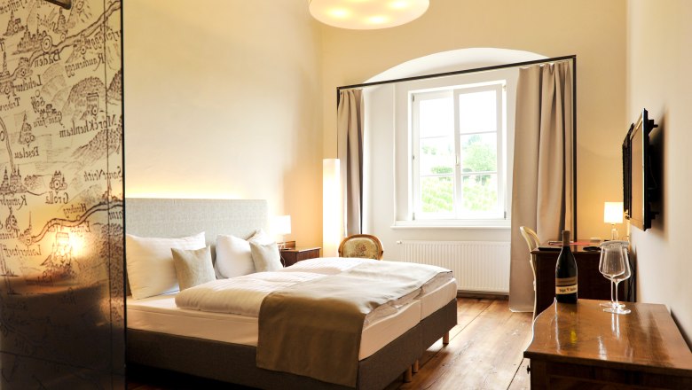 Elegantes Hotelzimmer mit Doppelbett, Holzboden und gro&szlig;em Fenster.