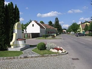 Stra&szlig;e in Mitterndorf an der Fischa mit H&auml;usern und Denkmal.