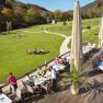 Terrace of the Krainerhütte seminar and event hotel with guests eating, surrounded by green meadows and forest.