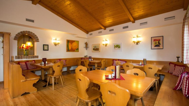 Gem&uuml;tliche Stube mit Holzm&ouml;beln, karierten Kissen und Wanddekorationen.