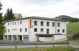 Ein wei&szlig;es Geb&auml;ude mit der Aufschrift 'Brandtner' in l&auml;ndlicher Umgebung.