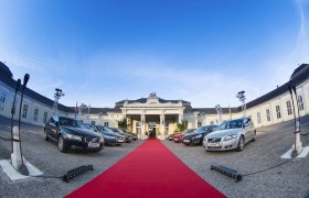 Eingang des Conference Center Laxenburg mit geparkten Autos und rotem Teppich.