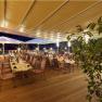A festively decorated terrace with tables and chairs under a large sunshade at night.