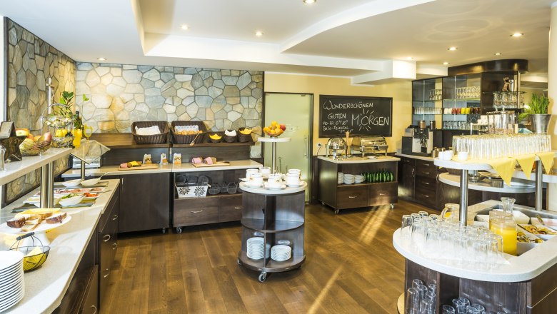 Ein Frühstücksbuffet mit verschiedenen Speisen und Getränken in einem hellen Raum.