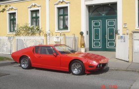 Gelbes Geb&auml;ude mit gr&uuml;ner T&uuml;r und rotem Auto.