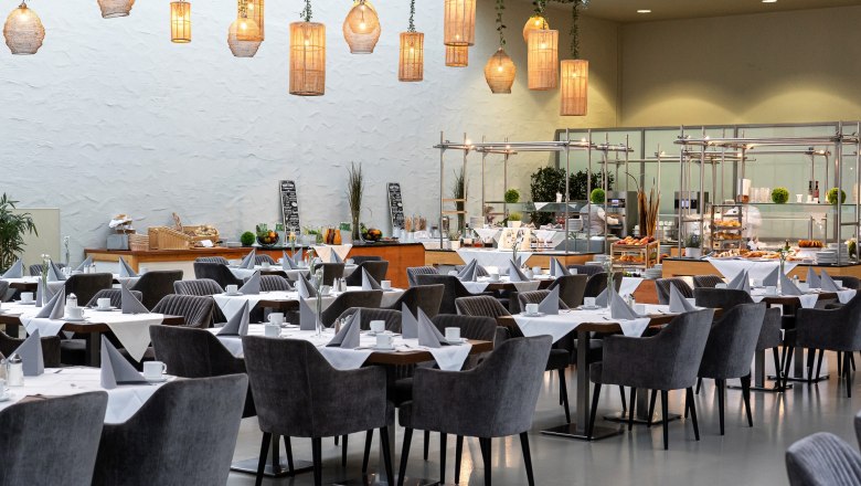 Innenansicht eines stilvollen Restaurants mit gedeckten Tischen und hängenden Lampen.